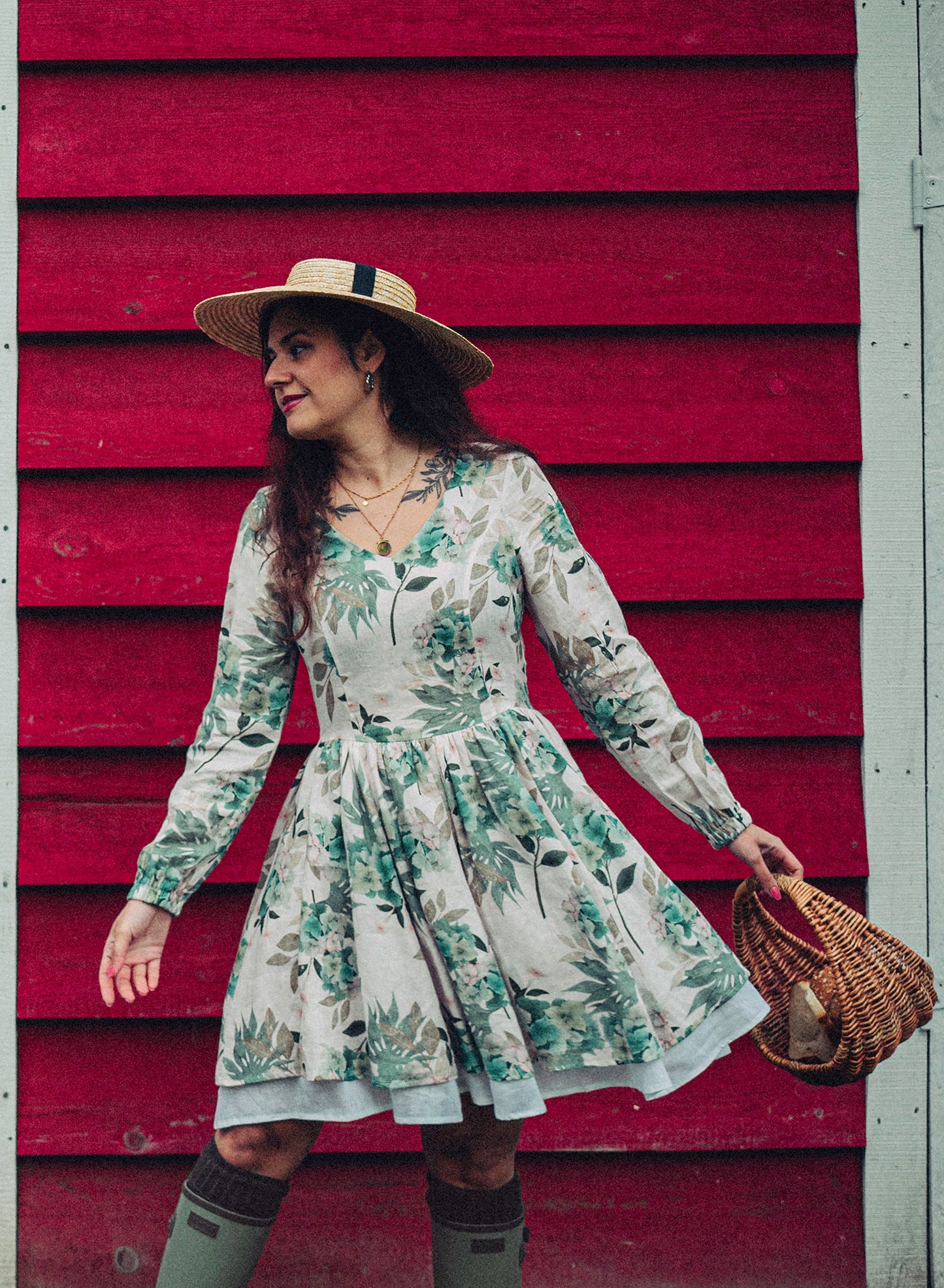 Woman wearing a long sleeve ivory dress with hydrangea flowers print made in house. Dress has a short skirt with pockets and white underskirt trim