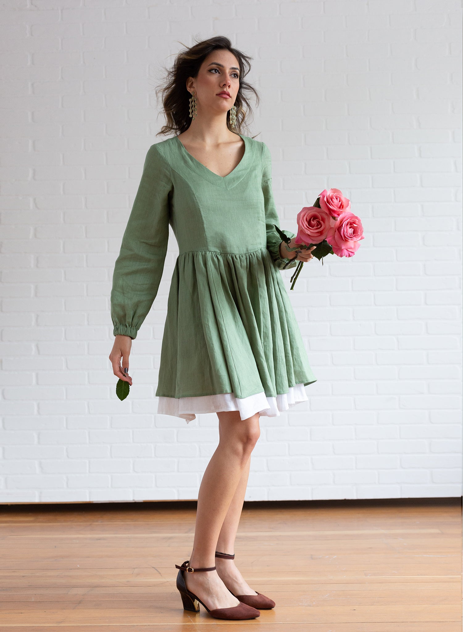 Woman wearing a linen long sleeve and v-neck prairie dress and holding flowers